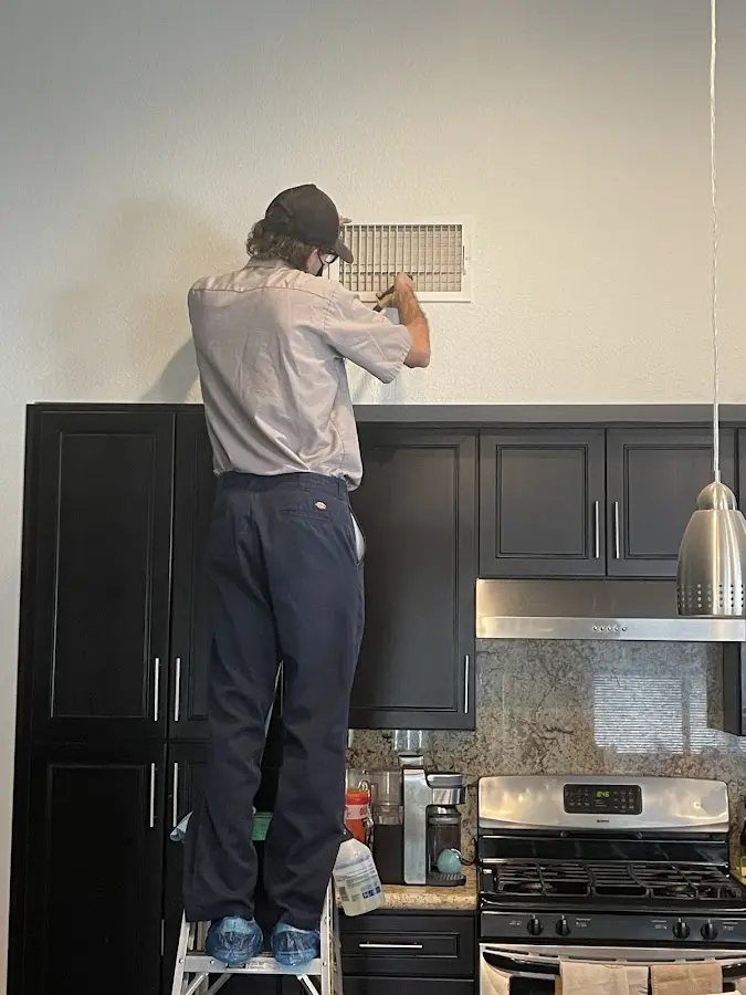 Technician inspecting an air vent during HVAC service in Fairfax